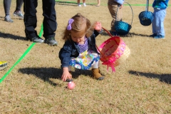 little girl picking up egg
